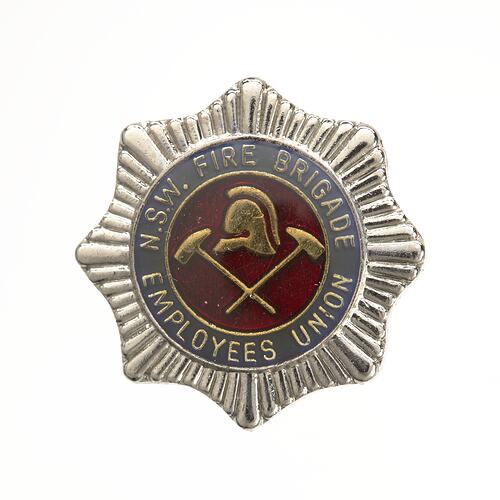 Silver star badge with blue then red enamel centre circle with gold helmet and 2 crossed hammers.