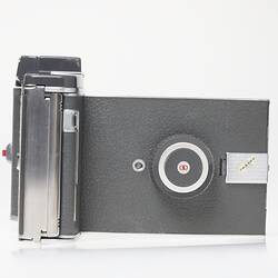 Front cover of grey steel camera with silver trim and leather handle.