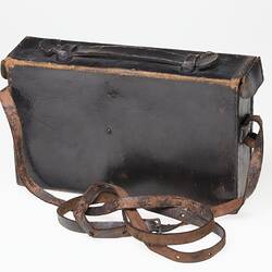 Back of dark brown (black faded?) leather camera carry case with strap.