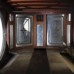 Black wooden hearse, internal view. Decorative oval glass paned cabin.