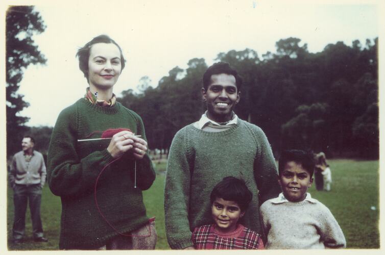 Woman knitting, man and two children standing in a park