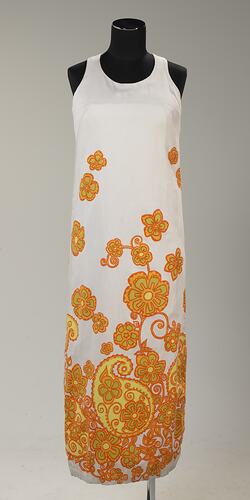 Long sleeveless white cotton dress with orange and yellow floral printed pattern.