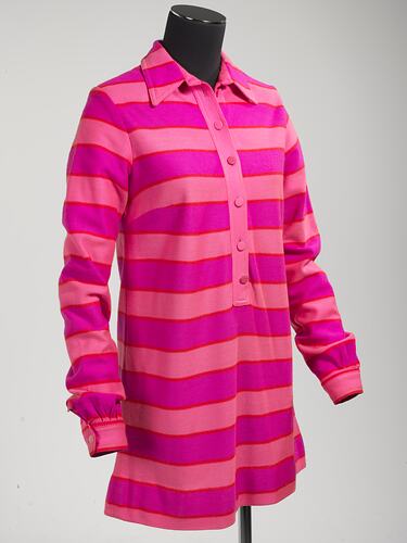 Angle view of pink striped mini polo-shirt dress. Long sleeve with collar, cuffs, front buttons.