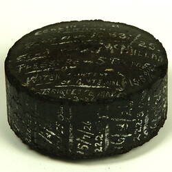 Black cylinder with white handwritten inscription.