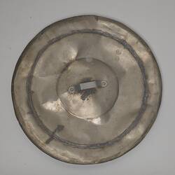 Round scuffed metal lid with lip.