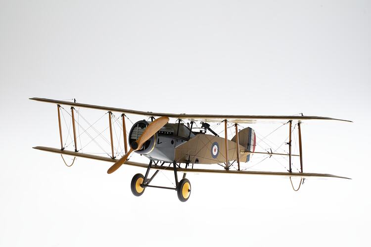 Model biplane aeroplane painted mustard brown with grey engine. Three quarter left view.