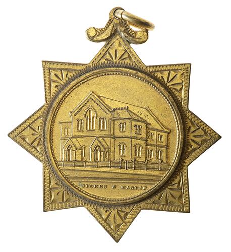 Gold medal set in 8-pointed star with loop. Features Wesleyan church building.