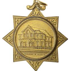 Gold medal set in 8-pointed star with loop. Features Wesleyan church building.