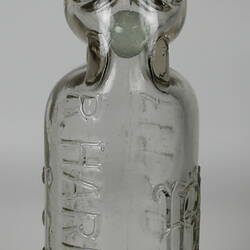 Clear glass bottle with raised inscription.