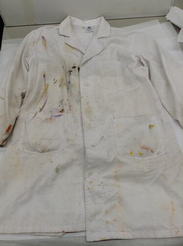 White lab coat spattered with coloured paint.