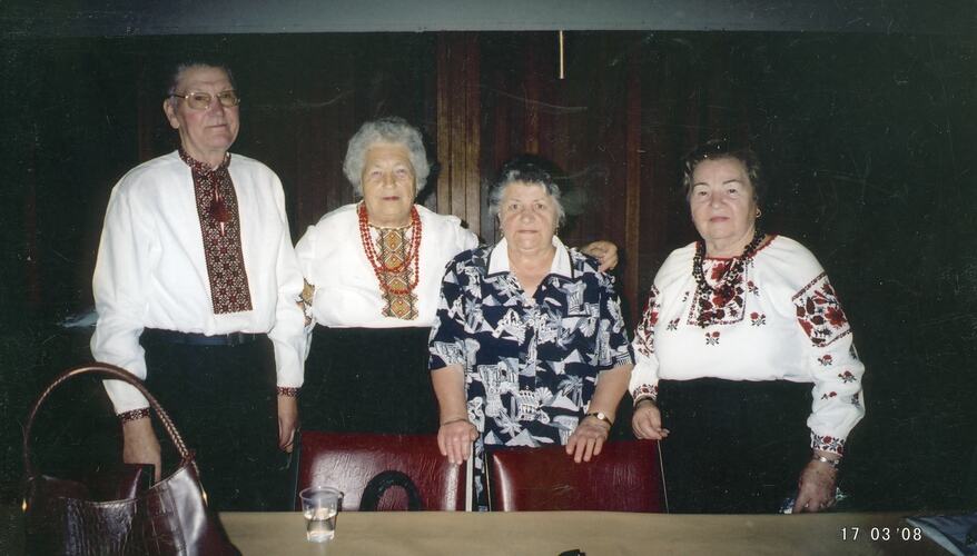 Four people pose, three wearing Ukrainian national dress.