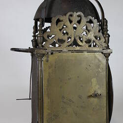 Rectangular metal clock with domed top, side view.