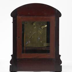 Back of mantel clock. mahogany case. Small glass door shows internal mechanism.