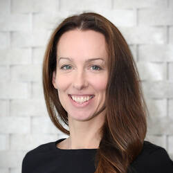A close up shot of a smiling white woman with blue eyes and long brown hair.
