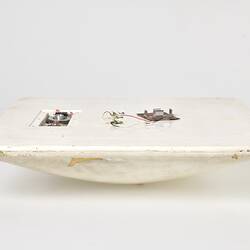 Scuffed white plastic square plate with curved base and rounded corners. Profile.