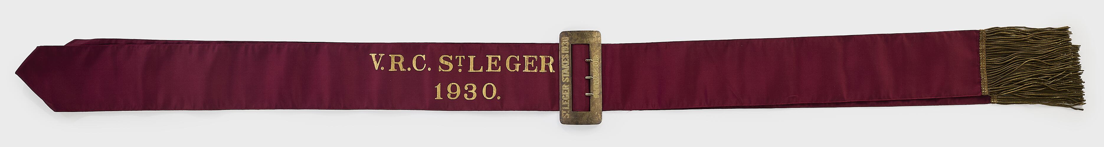 Burgundy ribbon sash with gold lettering, buckle and fringe.