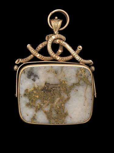 Rectangular pendant featuring white gold-bearing quartz in a gold setting, complimented by a delicate branch-like motif at the top.