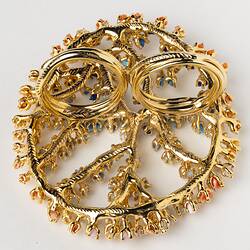 Underside view of large-scale, two-fingered, open work gold ring set with multicoloured microplastics.