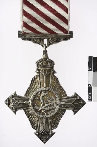 Four pointed medal with white and red ribbon.