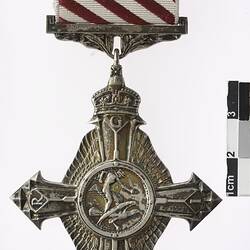 Four pointed medal with white and red ribbon.
