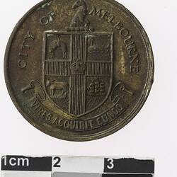 Round rusted medal with coat of arms, text surrounding.