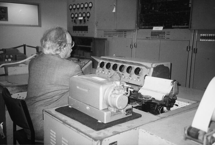 Man seated at desk operating console.