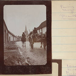 Man driving horse and carriage down street with two men on horseback behind.