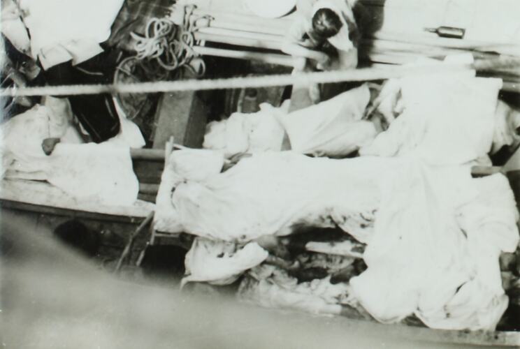 View from above of a lifeboat with passengers covered in sheets and bandages.