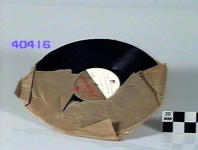 Record partially wrapped in ripped brown paper.