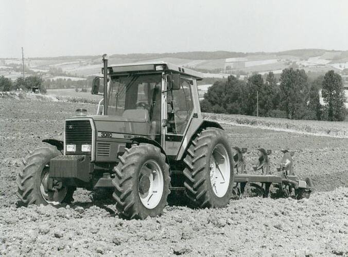 Man driving a tractor and mouldboard plough in field in English countryside.