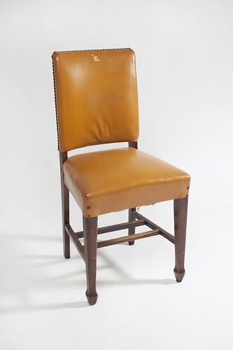Yellow furnished chair with dark wood legs.
