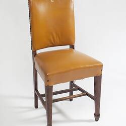 Yellow furnished chair with dark wood legs.