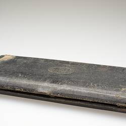 Closed, rectangular, worn, brown embossed leather case.