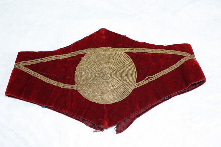 Child's wide scalloped edged red velvet belt (folded) with gold cord central circle and detail.