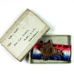 Open box with medal and red, white and blue ribbon.