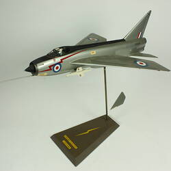 Silver model aeroplane. Blue, white and red rondels on wings and fuselage. On stand.