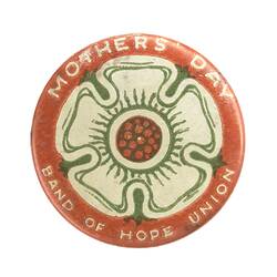 Round orange badge with white text and white/green/orange image of flower.
