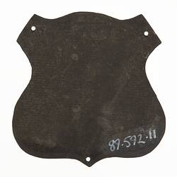 Back of shield shaped badge. Has three holes.