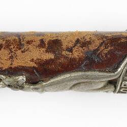 Detail of leather riding crop handle with silver cap and emblem.