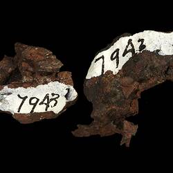 Two brown rock fragments with hand written numbers.