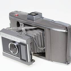 Camera, fold out, taupe leatherette cover, black lens plate, metal mechanism.