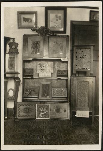 Room interior with wooden bookshelf holding numerous wooden  carvings.