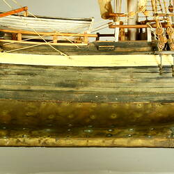 Wooden ship with three masts, side view.