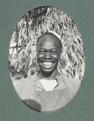 Young man smiling in front of vegetation.