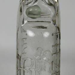 Clear glass bottle with raised inscription.