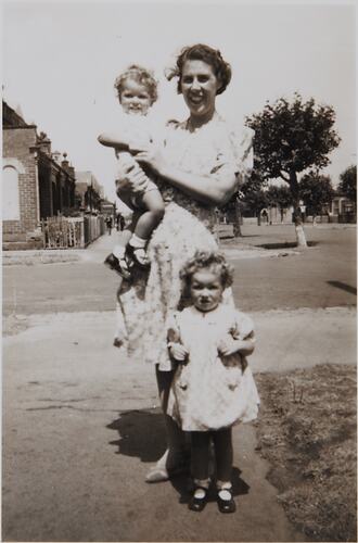Woman with two children standing on street.