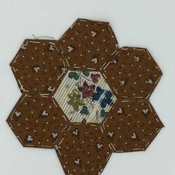 Brown hearts hexagonal coloured fabric patches that are stitched together. White striped floral centre.