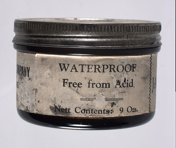 Glass jar of boot polish with screw-top lid and paper label.