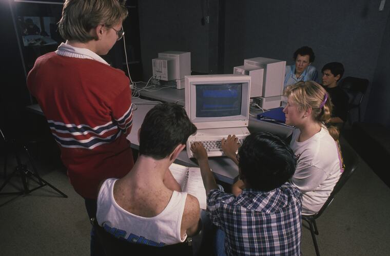 A group of students huddled around a computer.