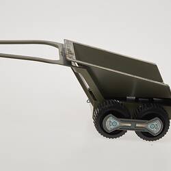 Plastic grey toy trailer with two wheels. Left profile view.